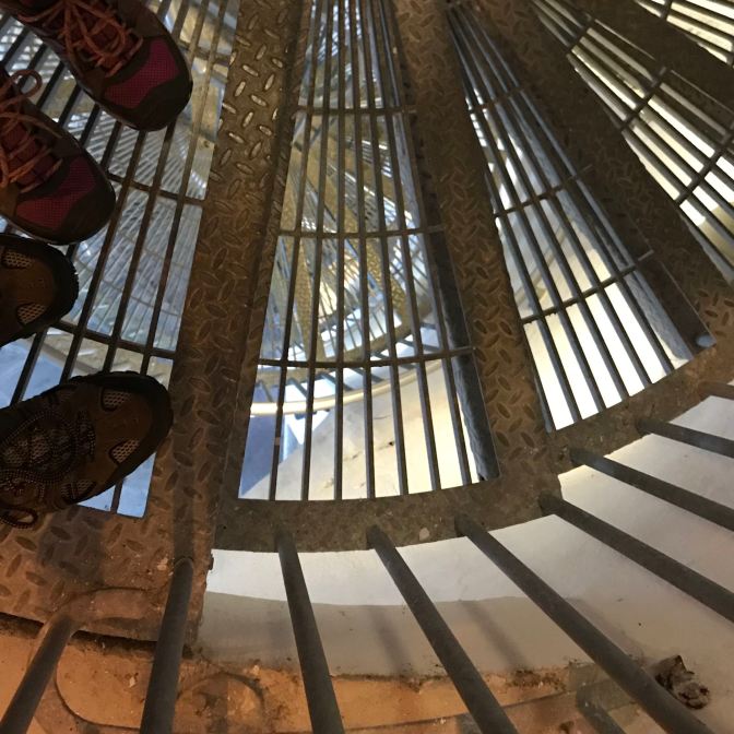 Feet in foreground of open staircase.