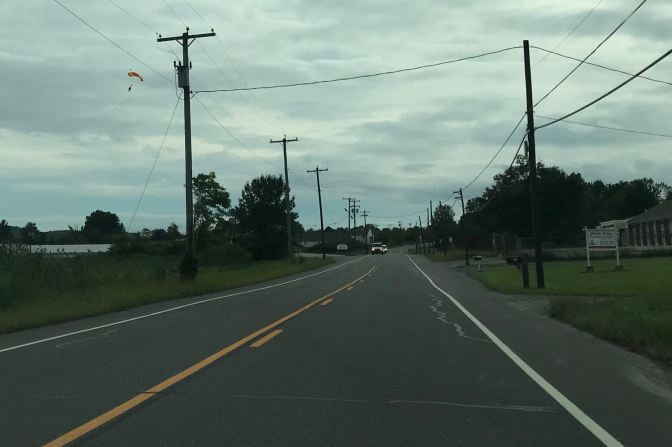 Sky diver floating over road.