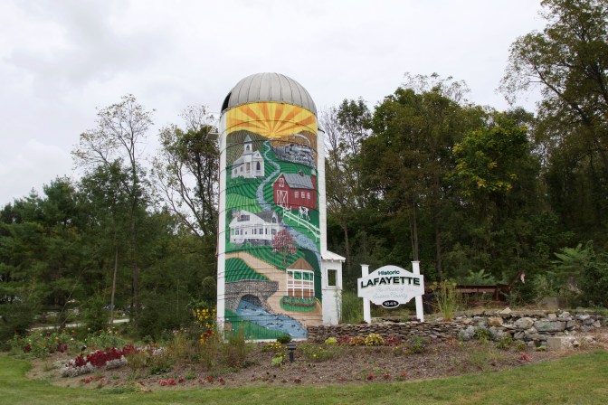Mural painted on a white grain silo. Beside it is a sign that reads HISTORIC LAFAYETTE.