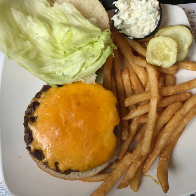 Cheeseburger, pickles, french fries, and coleslaw.