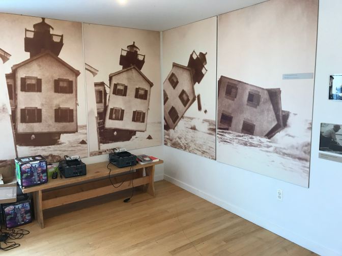 Four wall-size photographs showing Tucker Island Lighthouse falling into the ocean.