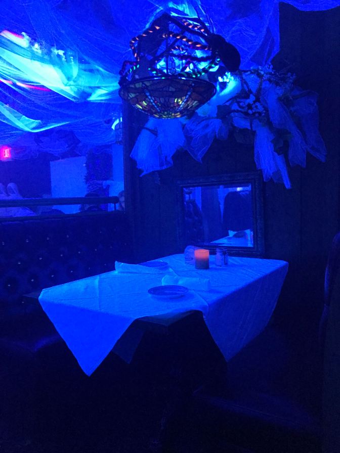 Room, illuminated in black light, decorated for Halloween.