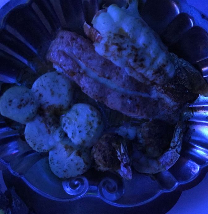 Plate of lobster tail, scallops, stuffed shrimp, and salmon.