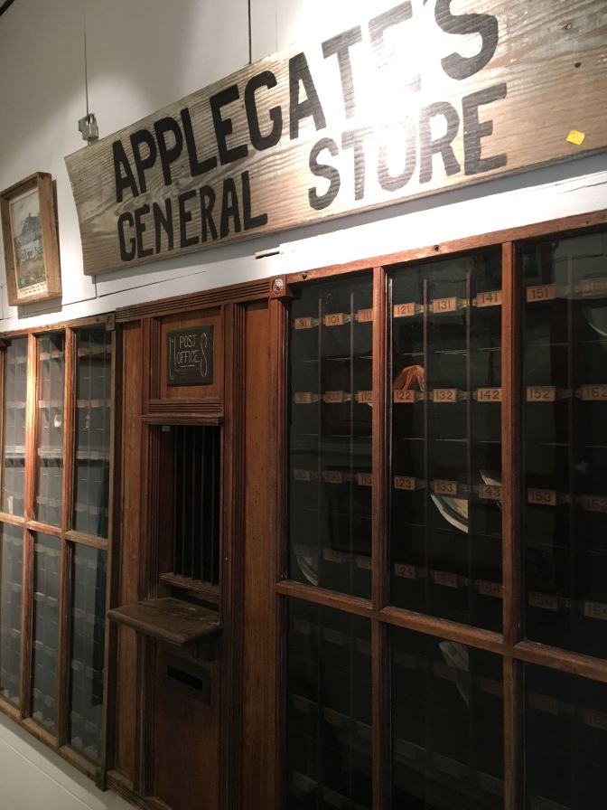 Facade of post office. A sign that says APPLEGATE'S GENERAL STORE is hung on the wall above it.