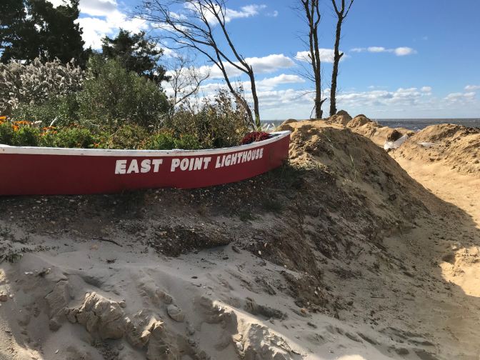 Sign on beach that says East Point Lighthouse.
