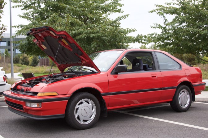 Red Acura Integra with its hood up.