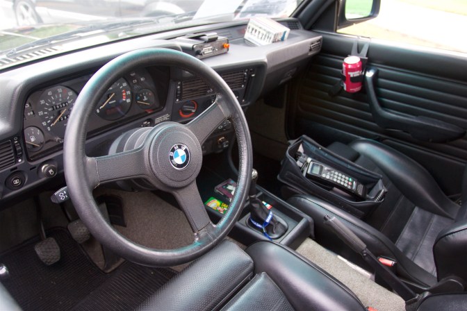 Interior of BMW 325i with old cell phone, radar detector, and cassette tapes.