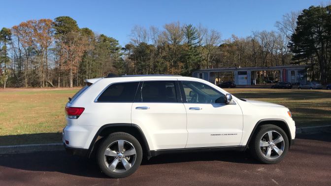 2014 white Jeep Grand Cherokee, parked in circular lot in front of main gate to WheatonArts.