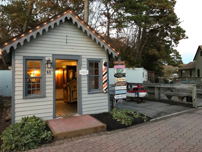 Small building with a series of signs beside it on a pole.