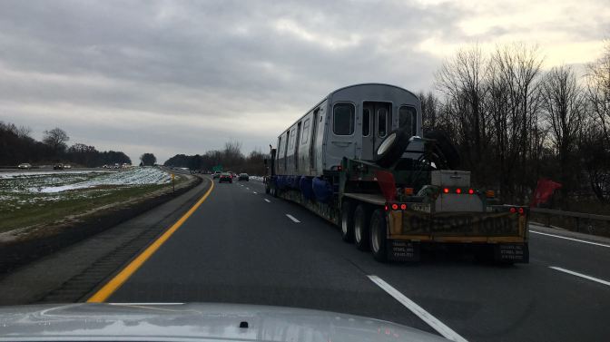 Train car on tractor trailer on highway.