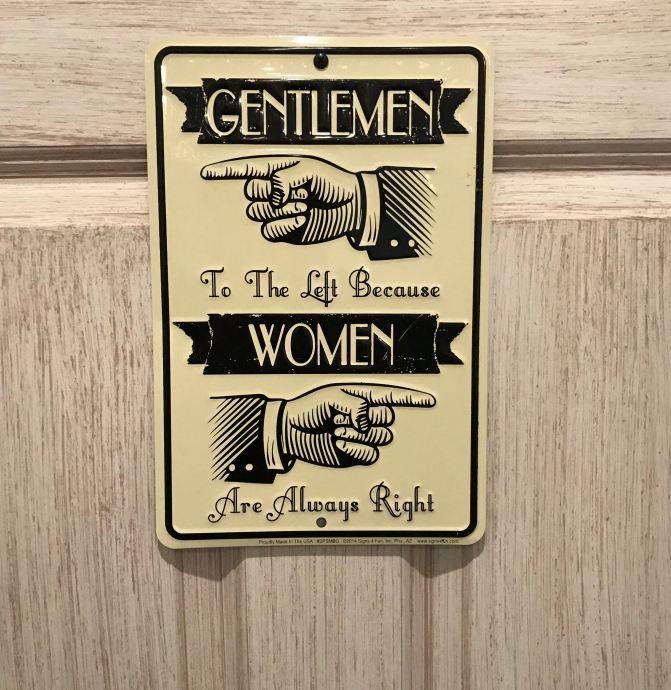 Sign that says GENTLEMEN TO THE LEFT BECAUSE WOMEN ARE ALWAYS RIGHT (hands point left and right).