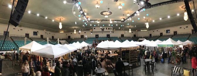 Interior of Convention Hall with white tents on the floor filled with vendors.