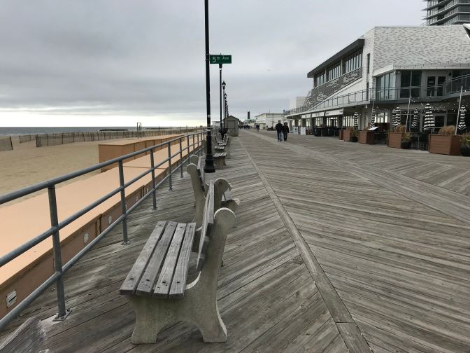 Bench along the Asbury Park Boardwalk. A sign for 5th Avenue is in the background on a pole.