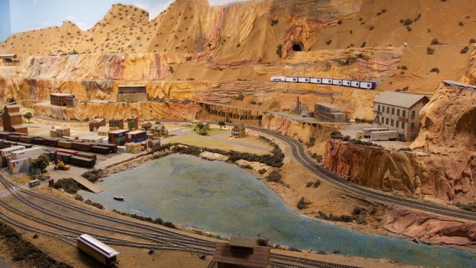 Desert canyon train set, with train yard and river in foreground.