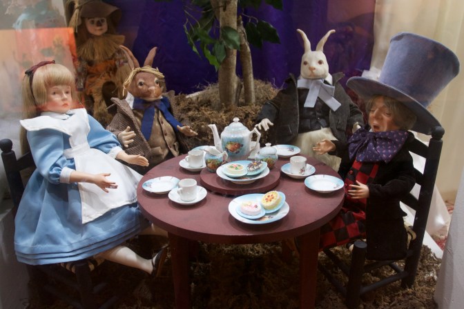 Alice in Wonderland doll exhibit with Alice and several other characters having a tea party.