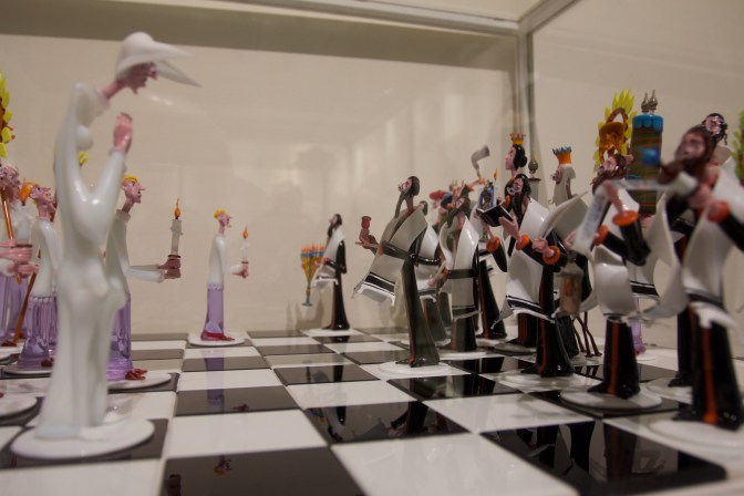 Chess set. The pieces are made of glass, and are figures dressed as Catholic clergy and Jewish religious leaders.