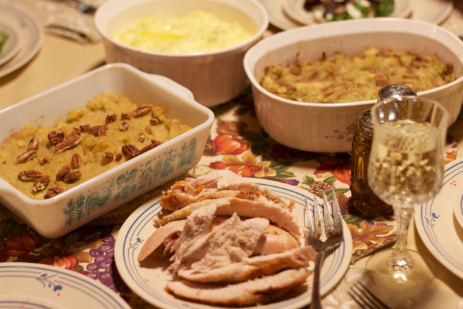 Table set for Thanksgiving, with turkey, sweet potato casserole, stuffing, and mashed potatoes.