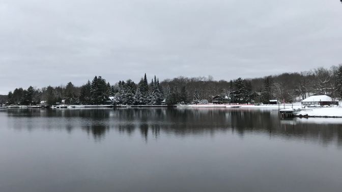 Snow-covered coastline alongside a lake.