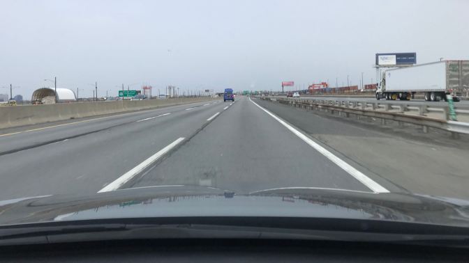 View of New Jersey Turnpike through the front windshield of a car.