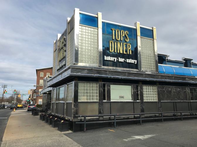 Photo of exterior of TOPS DINER. Sign on side of building says TOPS DINER BAKERY BAR EATERY.