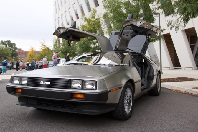 Silver Delorean DMC with its doors raised.
