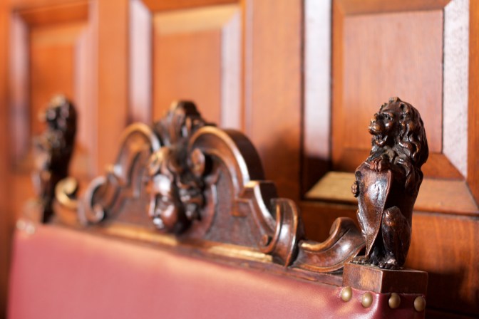 Lion carved into the top of a dining room chair.