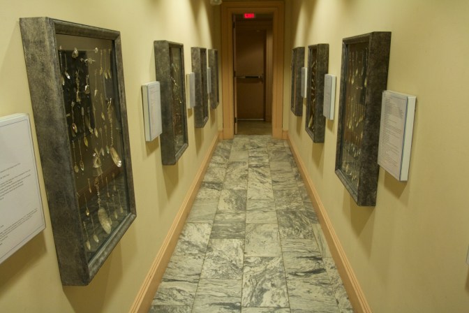 Hallway with spoons displayed in cases on either side.