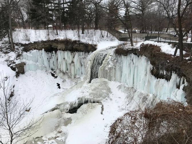 Nearly frozen Minnehaha Falls. A small channel of water runs in the middle of the falls.