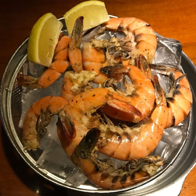 Shrimp in a bowl of ice, with lemon slices on the side.