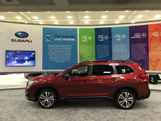 Subaru Ascent, in red in front of Subaru facade that says THE SUBARU LOVE PROMISE.