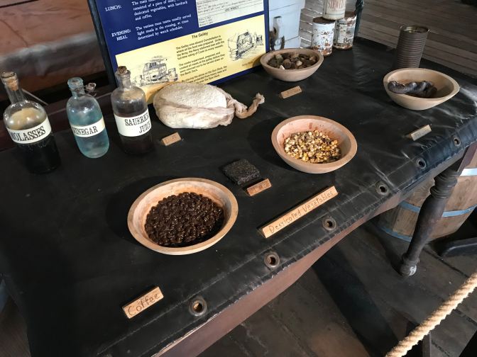 Table with bowls and bottles indicating typical fare for a seagoing vessel in the 19th century.