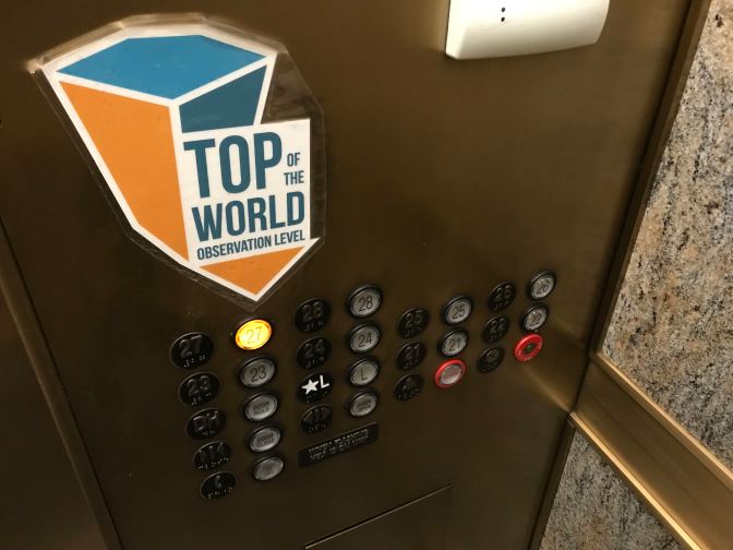 Elevator Buttons with a large sign that says TOP OF THE WORLD OBSERVATION LEVEL.