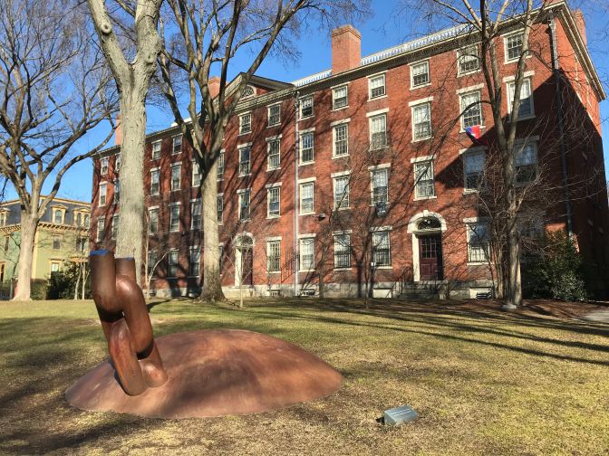 Broken chain sculpture in front of a brick dormitory.