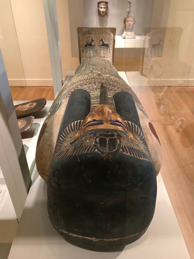Mummy, resting on a plinth in a glass case.