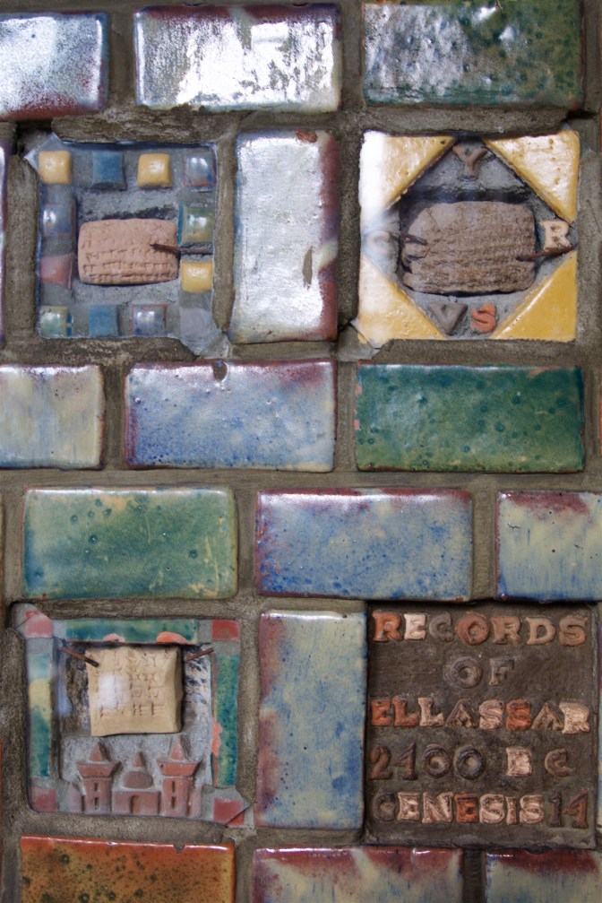 Cuneiform tablets embedded in pillar, surrounded by colored bricks. An encryption says RECORDS OF ELLASSAR 2400 BC GENESIS 14.