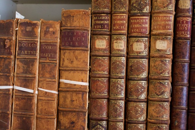 Old books, bound in leather, on a bookshelf.