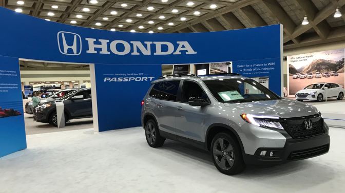 Honda Passport (silver) in front of blue facade that says HONDA - PASSPORT.