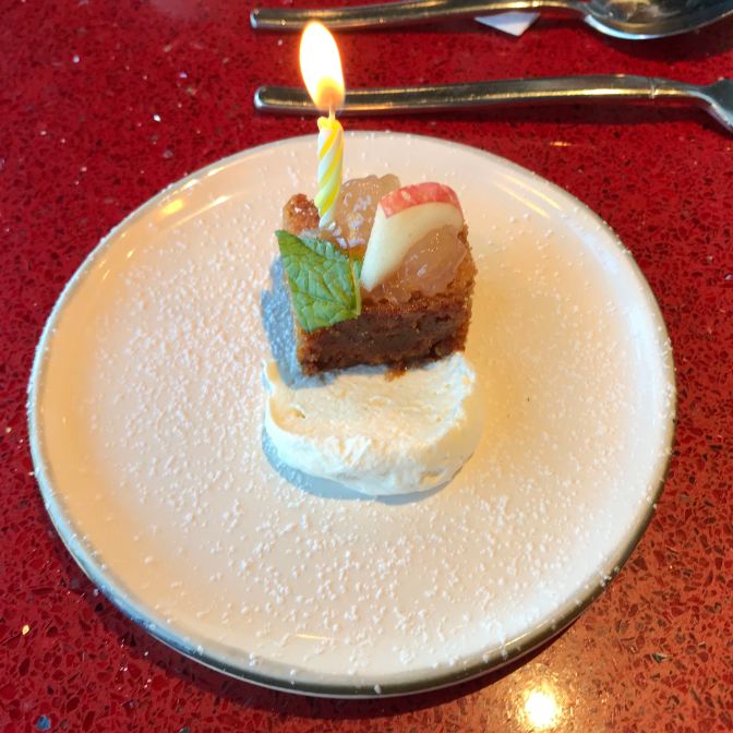 Apple cake on a white plate, with a candle in the cake.