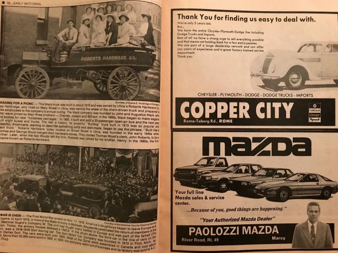 Magazine with photos of cars from the 1900s and 1920s on left, with car ads on the right for Copper City Chrysler Dodge Plymouth on top and Paolozzi Mazda on the bottom right.