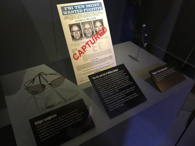 FBI TEN MOST WANTED FUGITIVE poster for James J. Bulger, along with Bulger's sunglasses and his lock-picking tool.