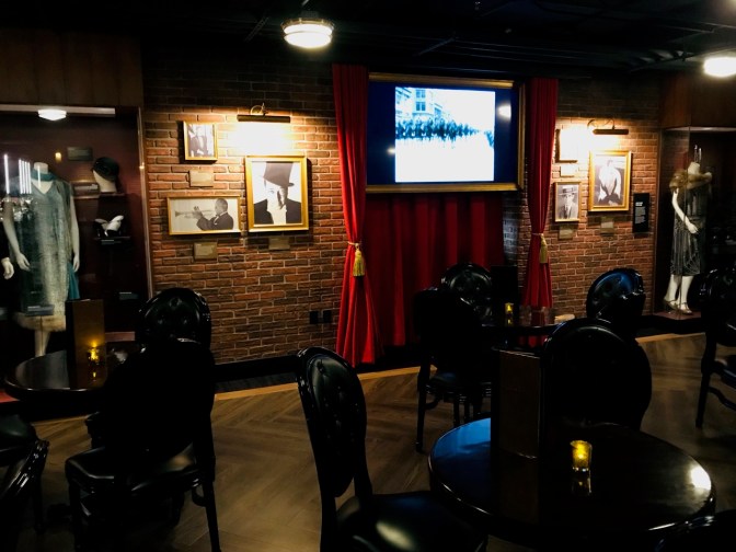 Basement speakeasy bar, with brick walls. Items from the 1920s adorn the walls, including "flapper" dresses.