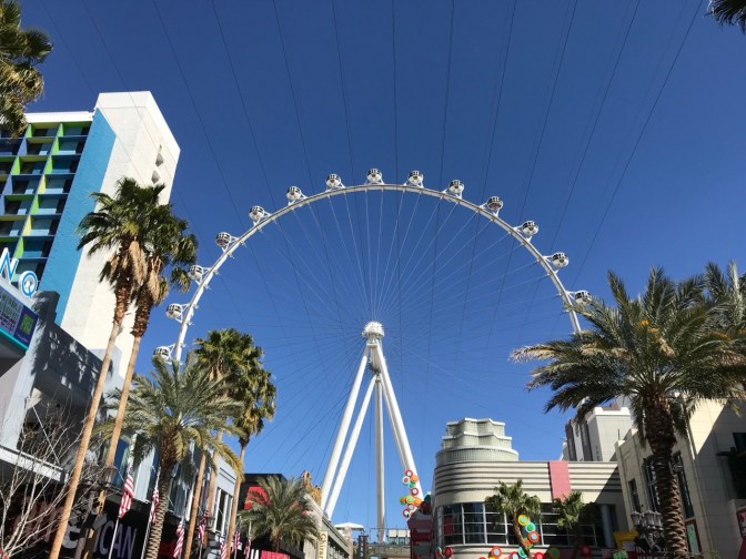 White Ferris Wheel towering over buildings on the strip.