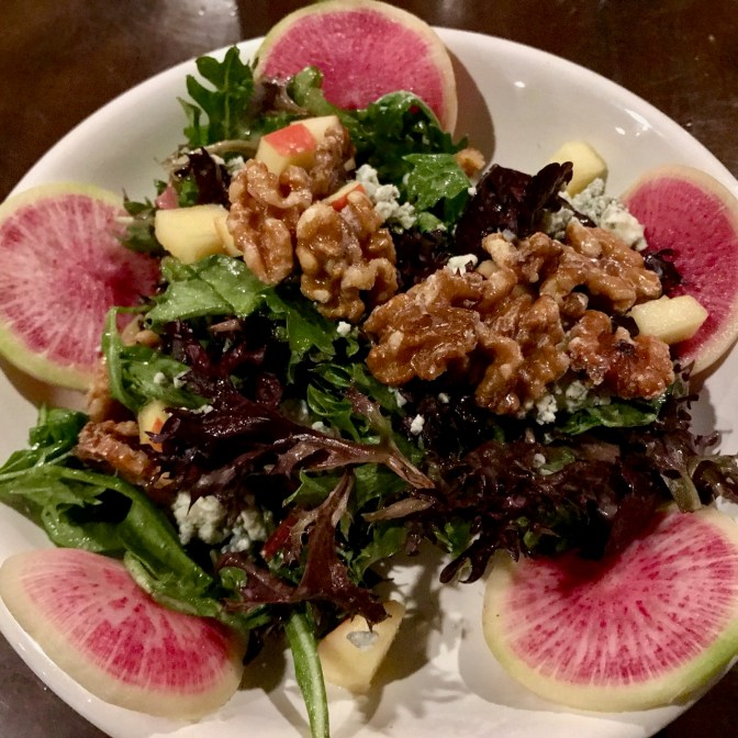 View of Therapy Signature Salad, with walnuts, greens, and watermelon radishes.