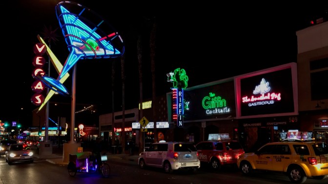 View of Freemont Street with neon signs including a martini glass and the word Vegas.