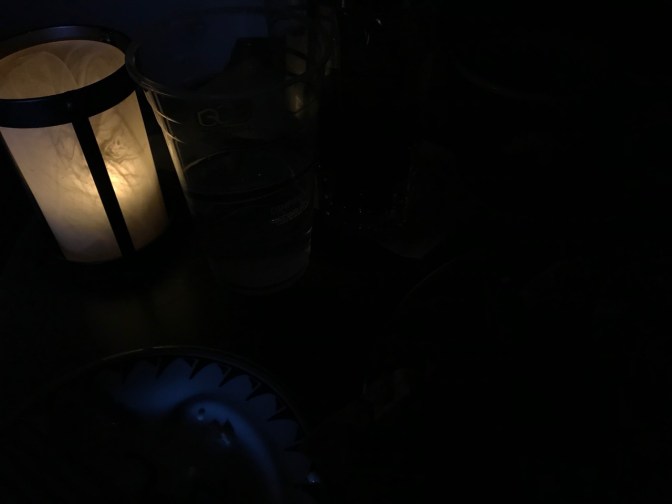 View of candle in blackened room.