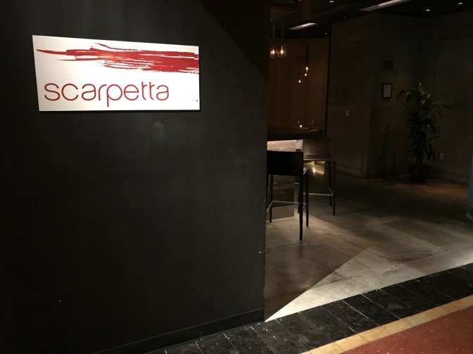 Exterior of Scarpetta restaurant, with a sign for Scarpetta on the wall.