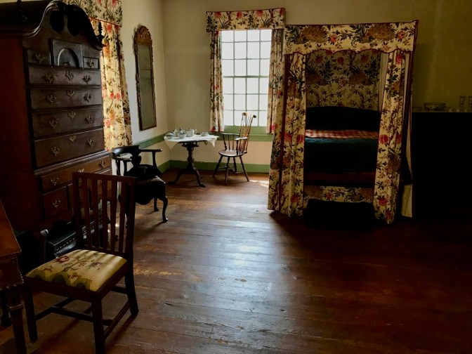 Interior of Washington's bedroom, with four-poster bed, chairs, table, and a large dresser.