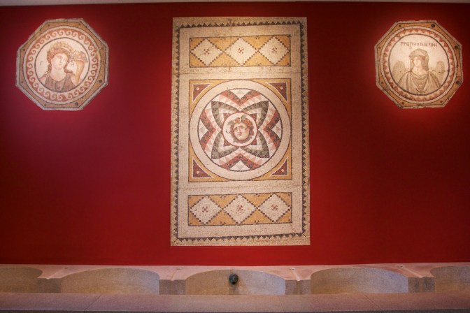 Three Roman mosaics on a red well.