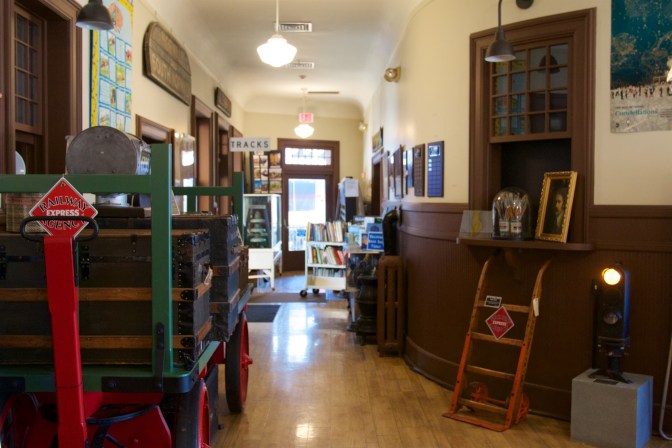 Interior of museum, with a ticket window on the right and a baggage cart on the left.