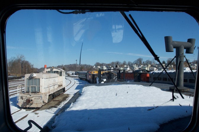 View of rail yard through upper windows of caboose. Numerous trains are visible.